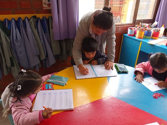 Die älteren Kinder bereiten sich mit einer Erzieherin auf die Schule vor