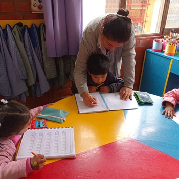 Die älteren Kinder bereiten sich mit einer Erzieherin auf die Schule vor