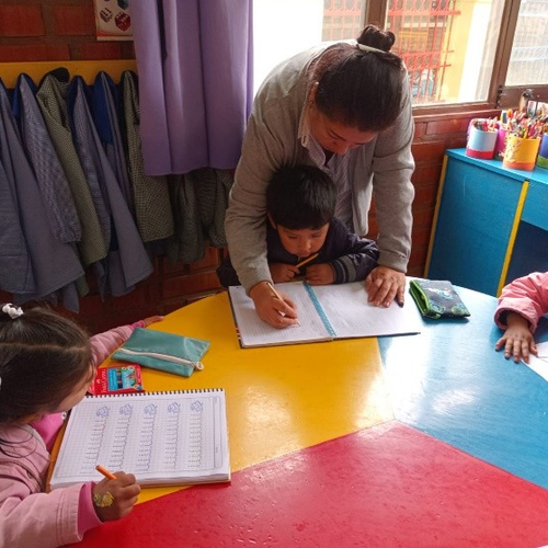 Die älteren Kinder bereiten sich mit einer Erzieherin auf die Schule vor.